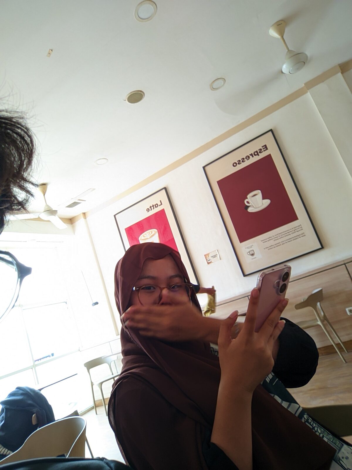 Nadhira sitting indoors while holding her phone