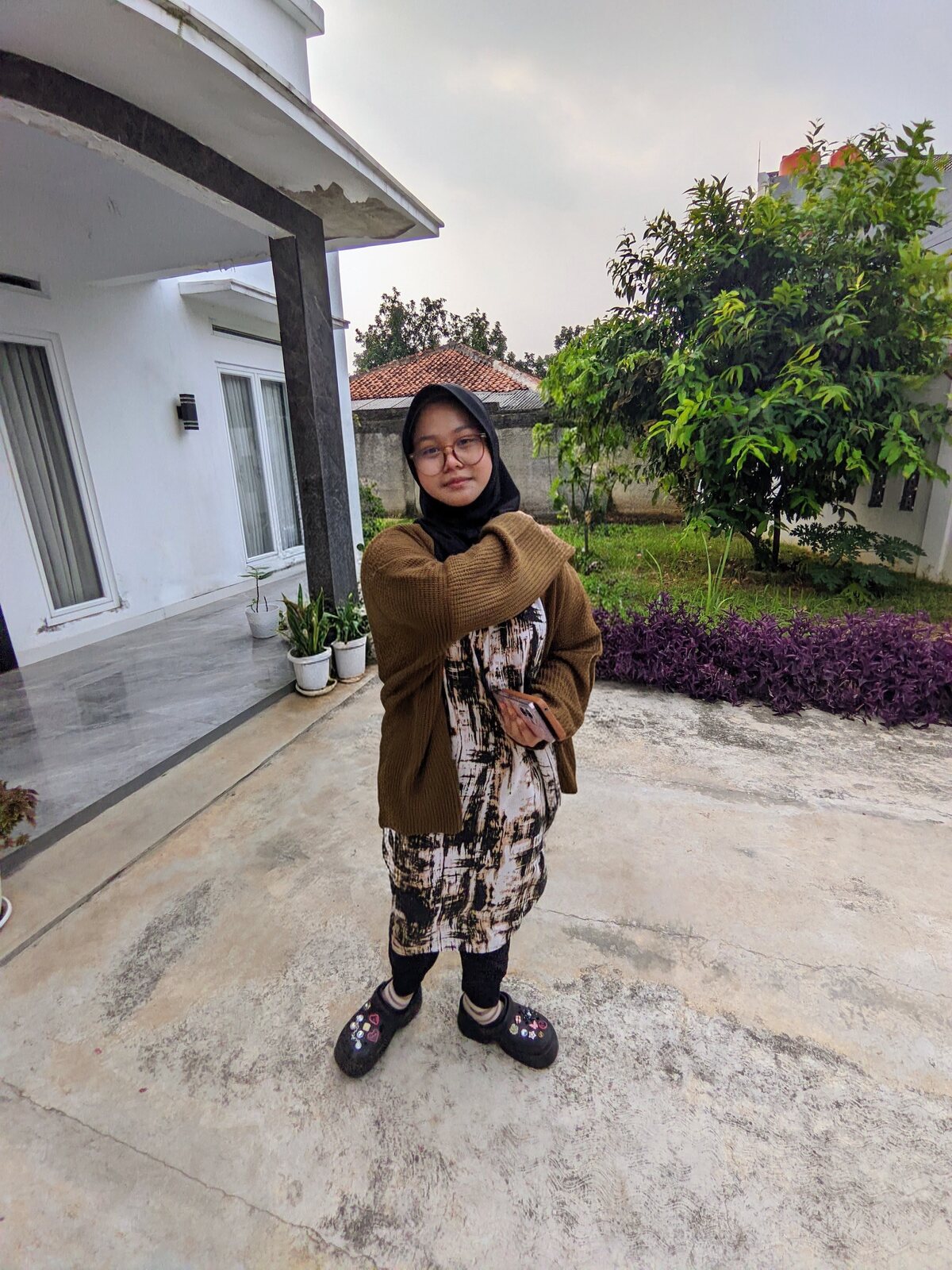 Nadhira posing outdoors in a brown hijab