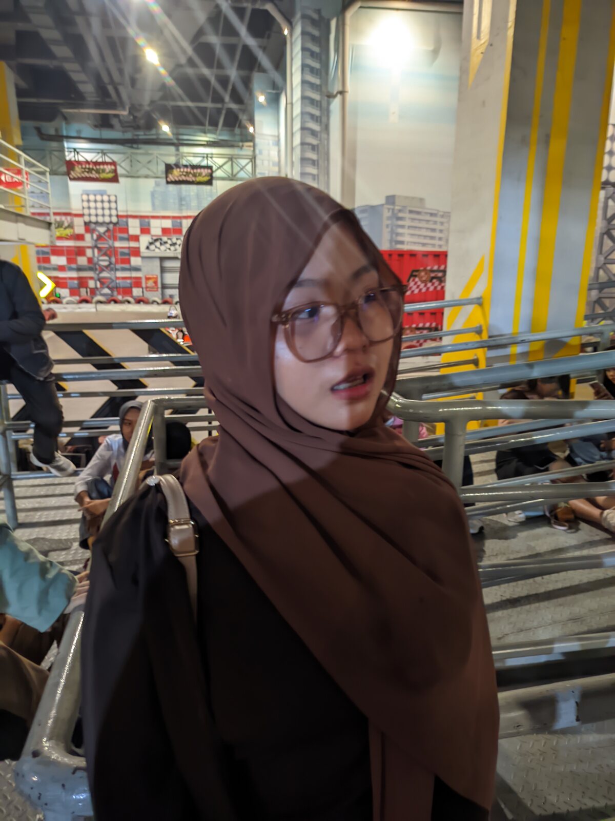 Nadhira standing indoors in a brown hijab