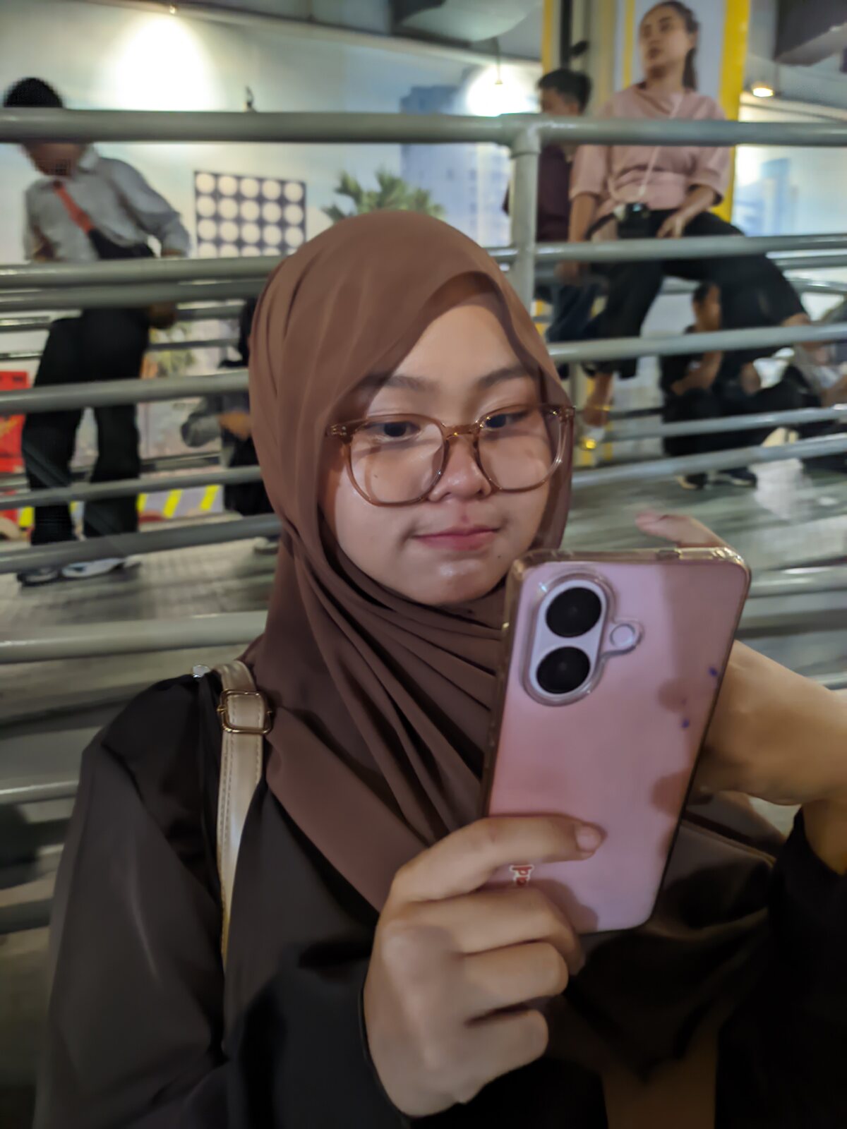 Nadhira taking a mirror selfie with a pink phone
